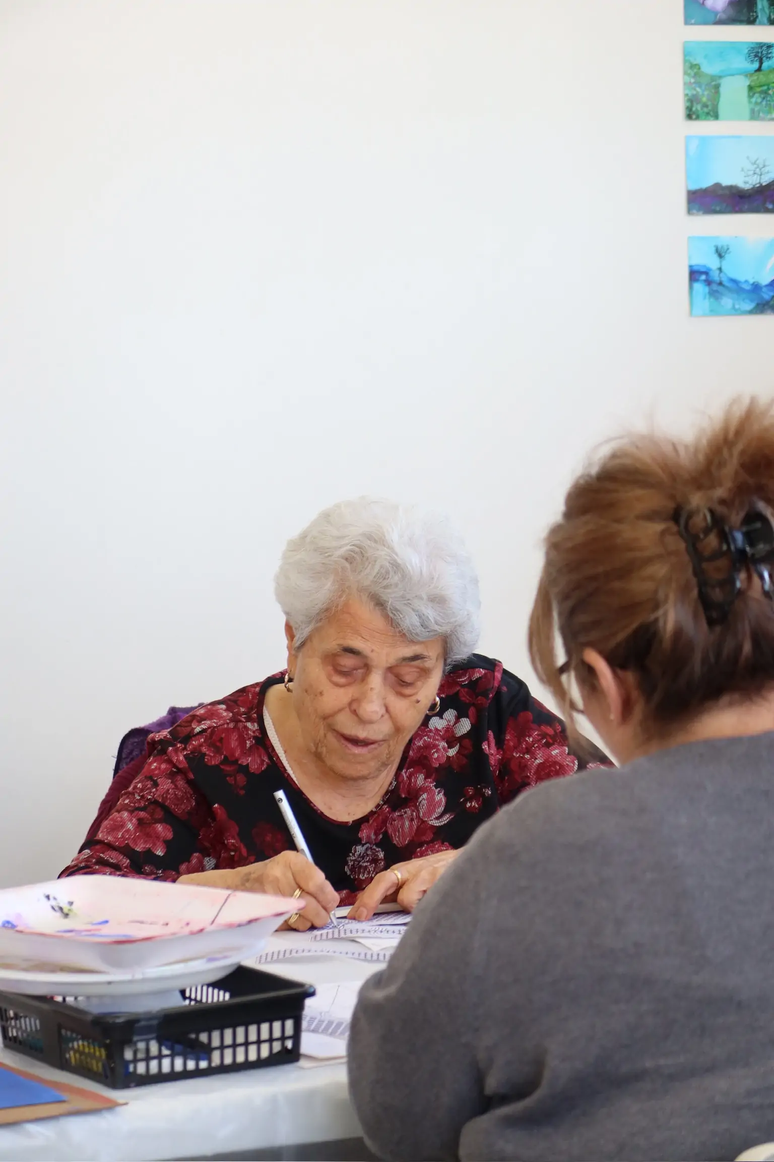 elderly woman participating in an art activity, writing on paper during a workshop