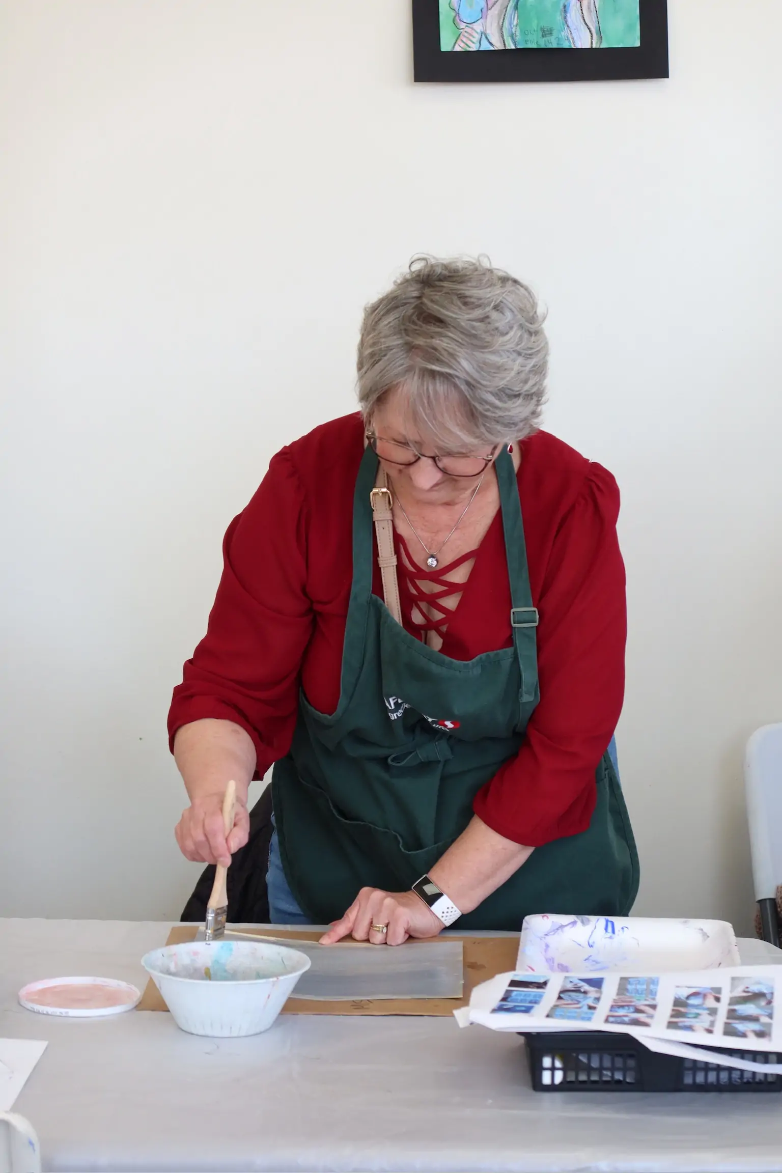 Woman working on a watercolor project at a table with art materials