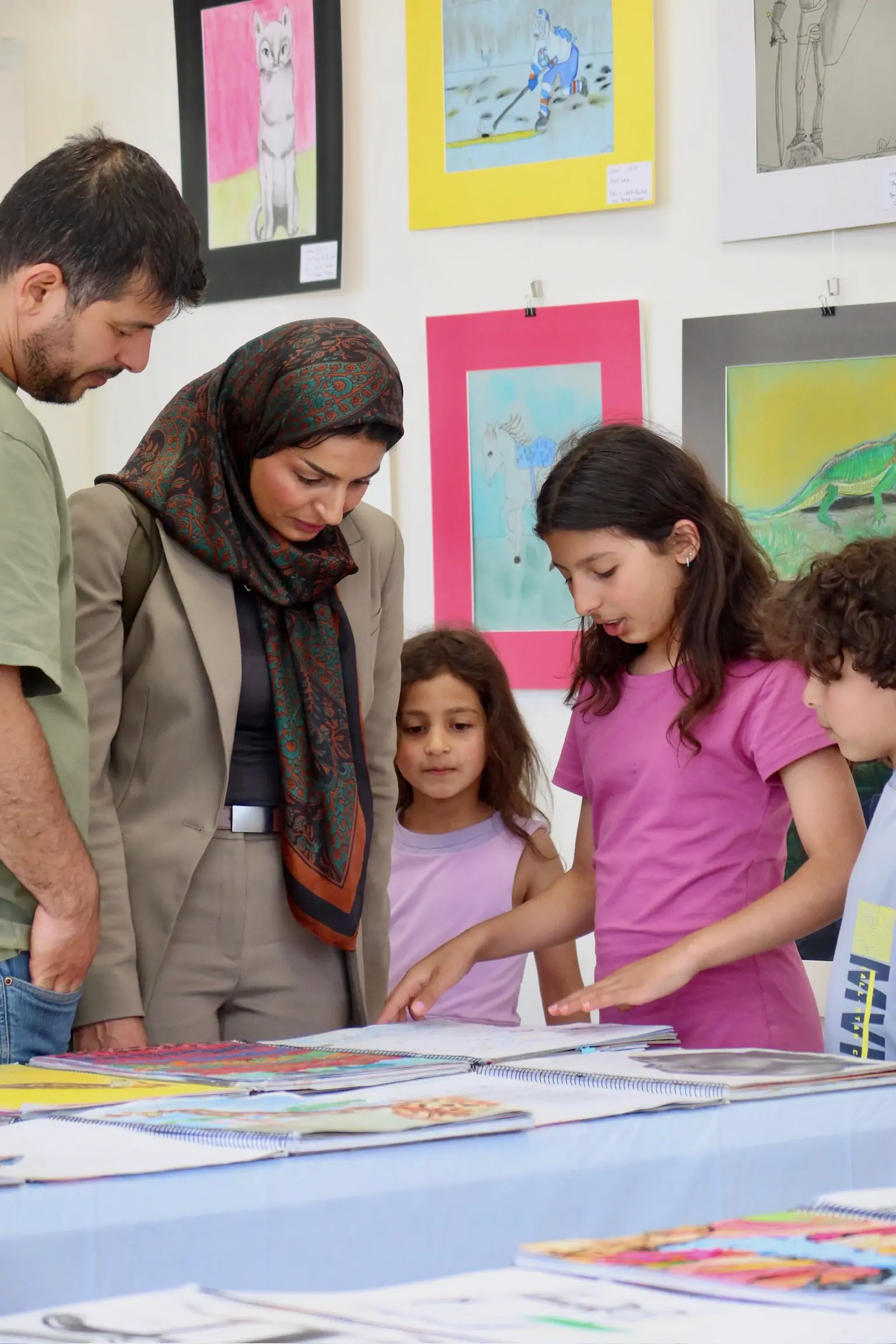Family viewing student sketchbooks and artwork together during the Aliki’s Art House showcase.