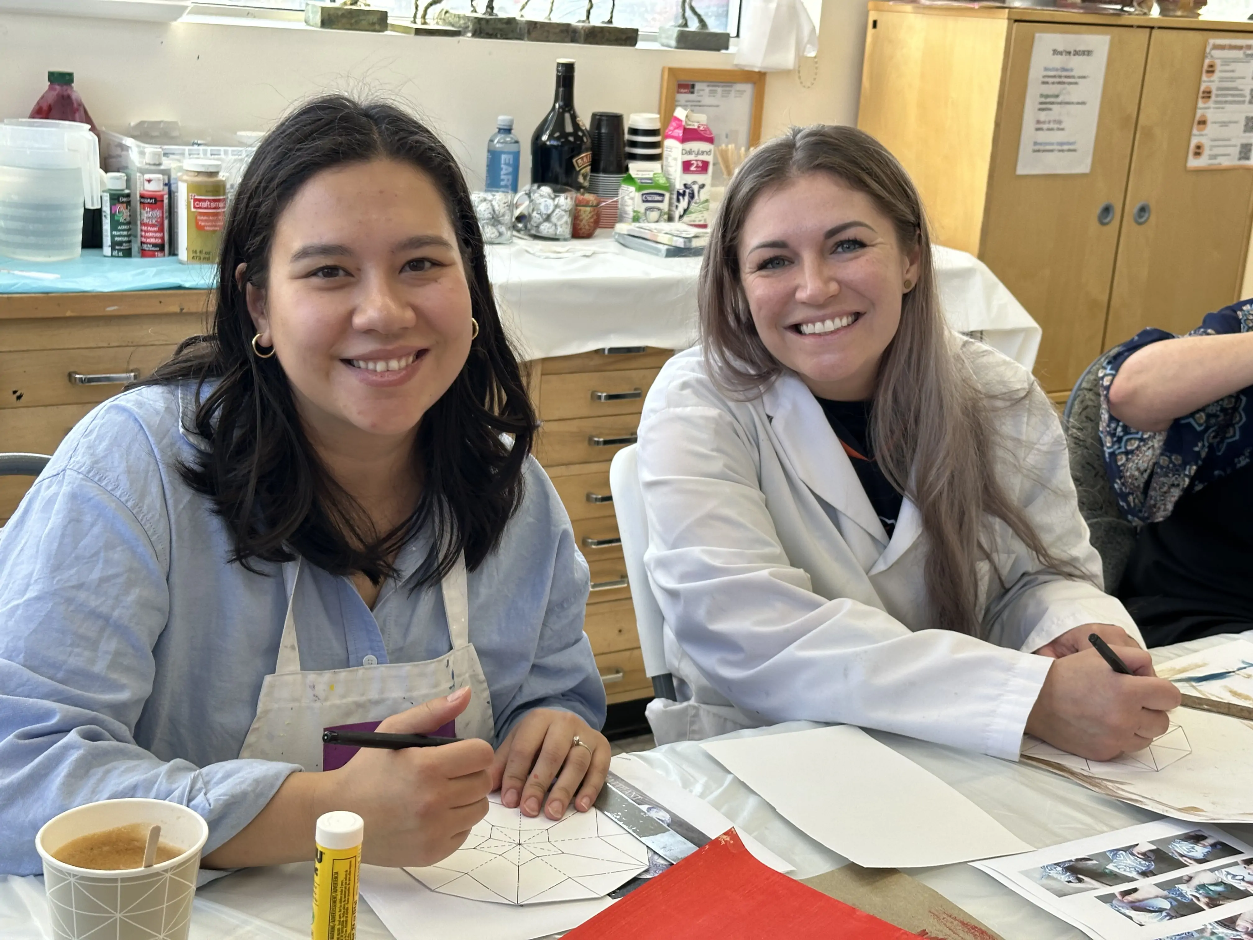 two adult students smiling while drawing geometric designs during an art workshop at Aliki’s Art House in Calgary
