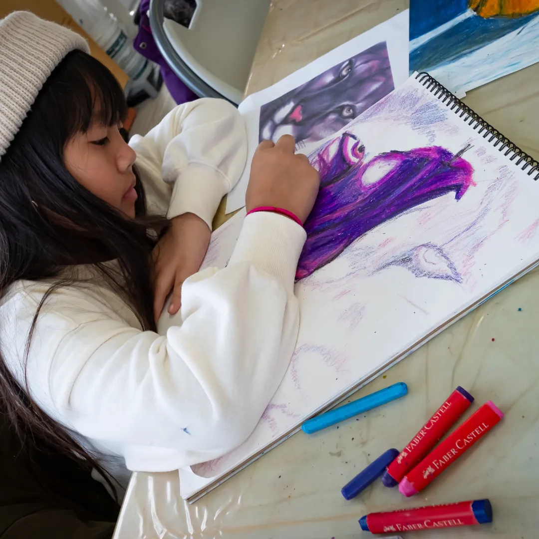 Student working on a colorful pastel drawing during the Advanced Drawing with Mixed Media class.