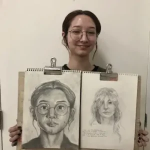 Student at Aliki’s Art House in Calgary holding two portrait drawings created in the Mastering Drawing from Life class for Teens and Adults.